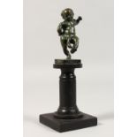 A MINIATURE BRONZE FIGURE OF A PUTTI, adorned with a large appendage, mounted on a pedestal. 7.
