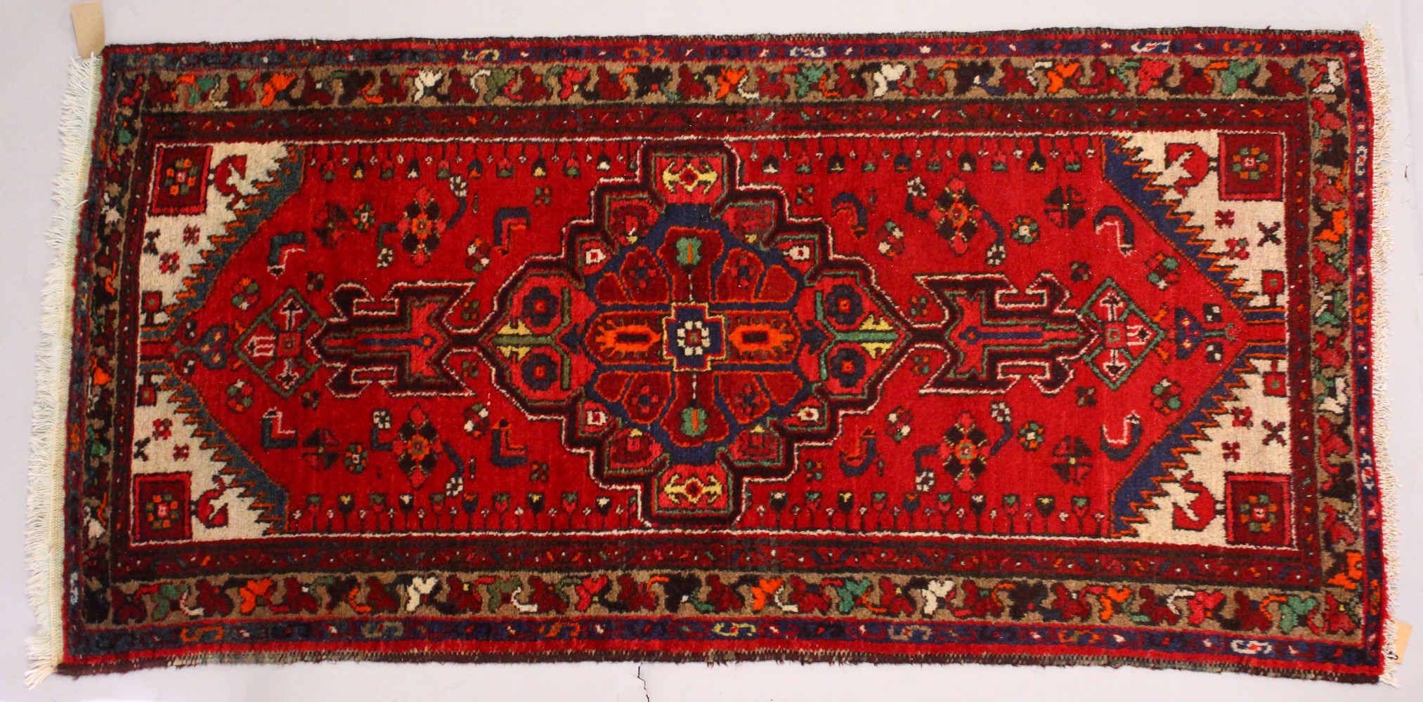 A PERSIAN RUG, with central motif and red ground. 7ft 2ins x 3ft 4ins.