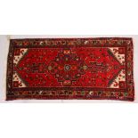 A PERSIAN RUG, with central motif and red ground. 7ft 2ins x 3ft 4ins.