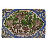 A QAJAR POTTERY TILE, decorated with a bird amongst flowers. 6.75ins x 4.5ins.