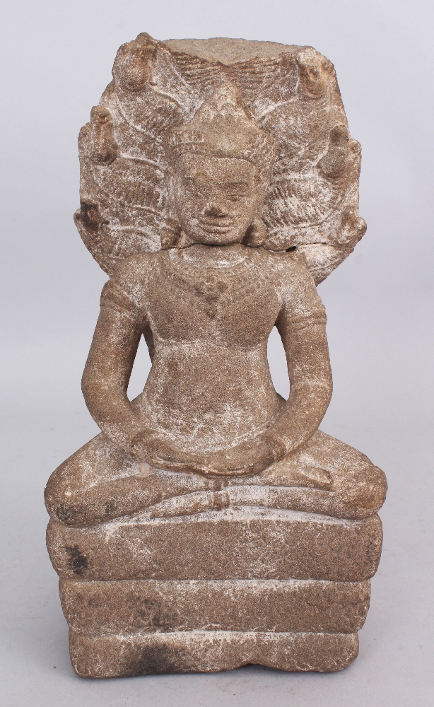 A Khmer Style Sandstone Figure of Buddha Seated under Mucalinda, seated in sattvasana on the