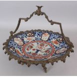 A GILT BRONZE MOUNTED JAPANESE IMARI PORCELAIN DISH, with overhead swing handle and on elaborate