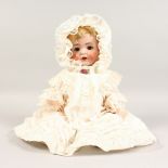 A GERMAN BISQUE HEADED DOLL, No. 40, with white bonnet and dress. 17ins long.