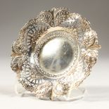 A VICTORIAN CIRCULAR PIERCED BONBON DISH, repousse with scrolls and flowers. 5.5ins diameter.