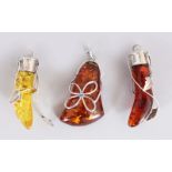 A SILVER MOUNTED AMBER PENDANT and TWO TOOTH SHAPED AMBER PENDANTS.