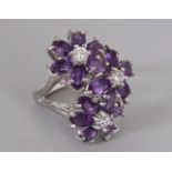 A LARGE TRIPLE FLOWER HEAD RING, set in silver.