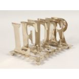A PLATED FIVE DIVISION TOAST RACK, with ladies spelling LETTERS. 8ins long.