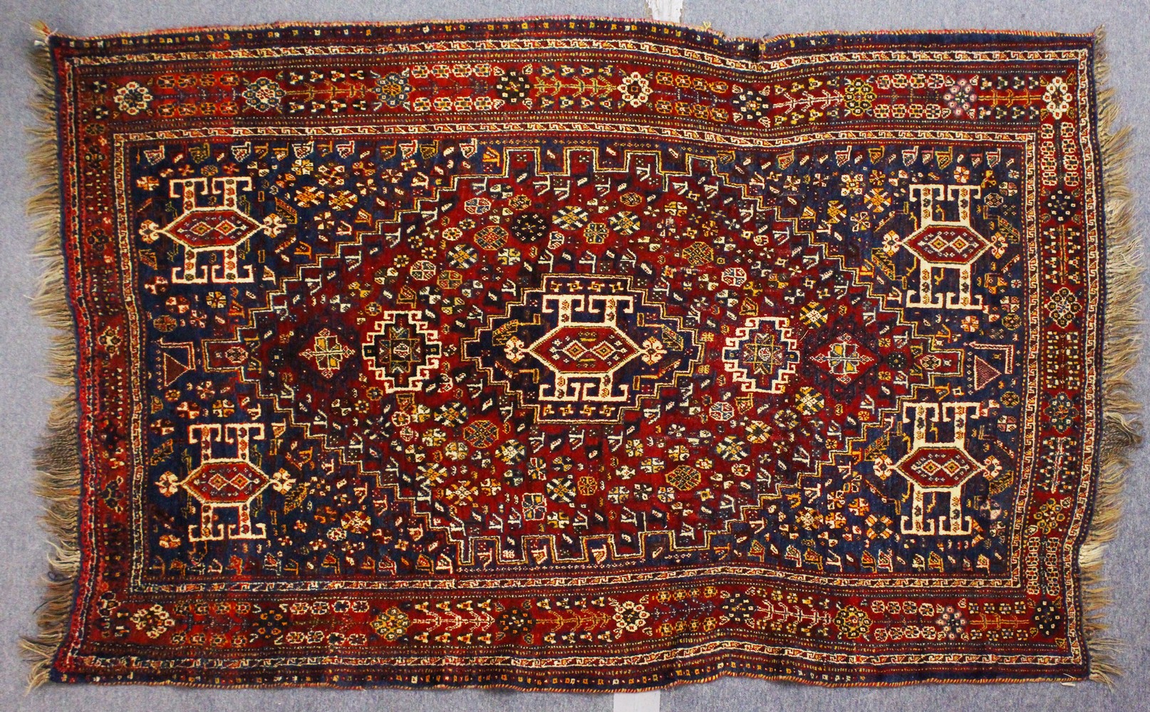 A PERSIAN CARPET, blue and red ground, decorated with stylised motifs. 8ft 3ins x 5ft 3ins.