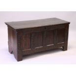 A 17TH CENTURY OAK COFFER, with plain plank top, over a four panel front with interlaced carved