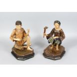 A PAIR OF 19TH CENTURY CARVED WOOD FIGURES, a seated woman holding a hammer, on stands. 12ins high.