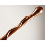 A WOODEN WALKING CANE, entwined with a snake. 35ins long.