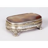 AN AGATE TOP CONTINENTAL SILVER BOX, supported on four claw feet. 5ins wide.