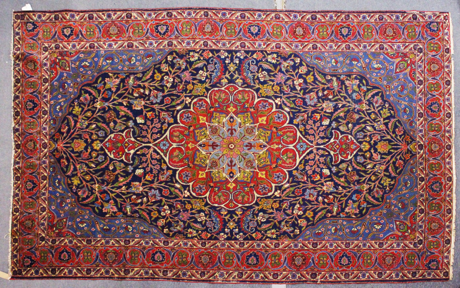 A PERSIAN CARPET, dark blue ground with central floral motif, within a similar border. 11ft 0ins x