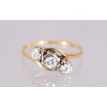 AN 18CT GOLD THREE STONE DIAMOND RING.