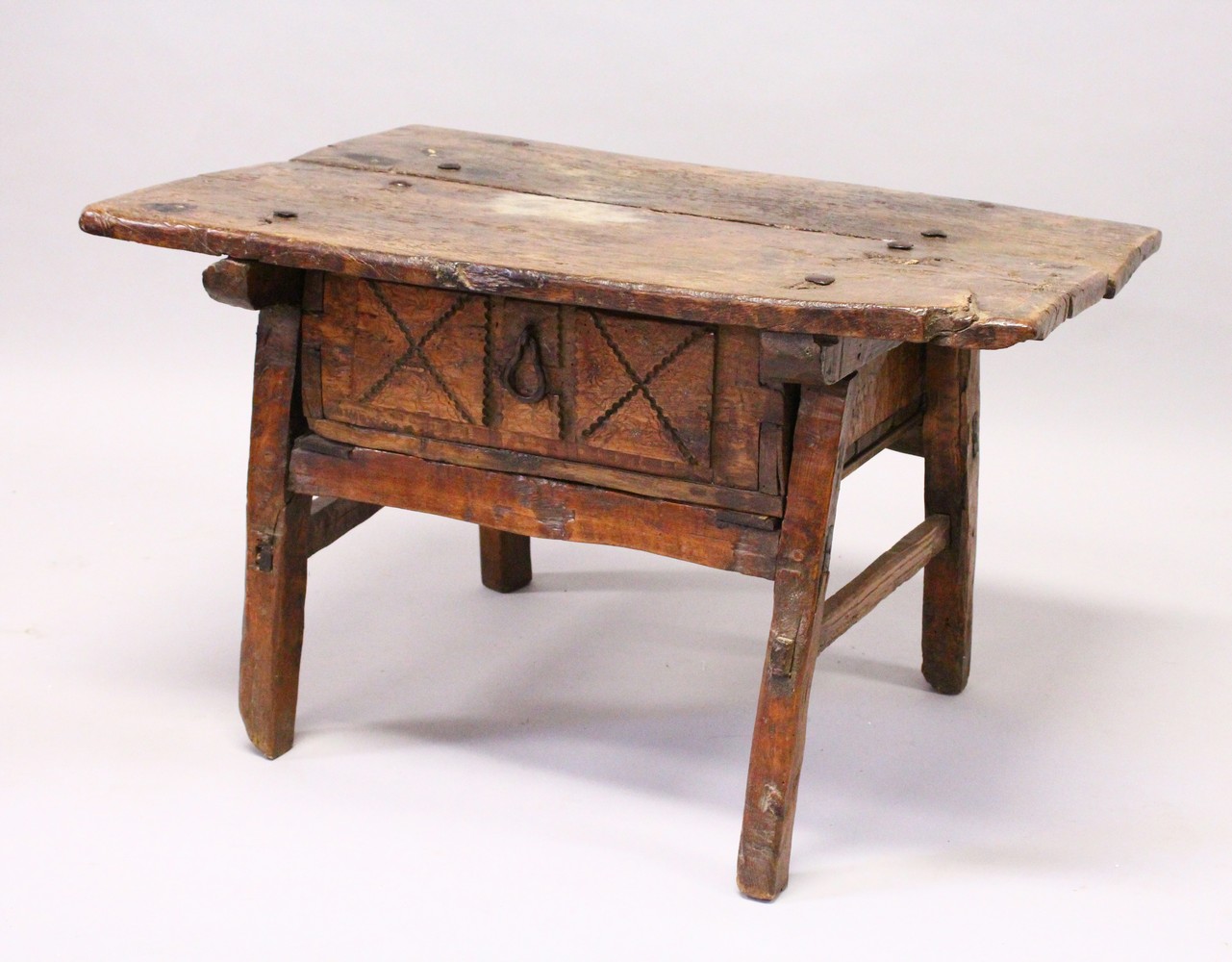 A 16TH CENTURY OAK RUSTIC LOW TABLE, with plank top over a drawer with carved decoration, a circular