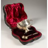 A TRIPLE HANDLED CIRCULAR CUP AND SIFTER SPOON in a fitted case. London 1906.