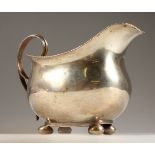 A GEORGE III MILK JUG, with gadrooned edge, on four ball feet. London 1809.