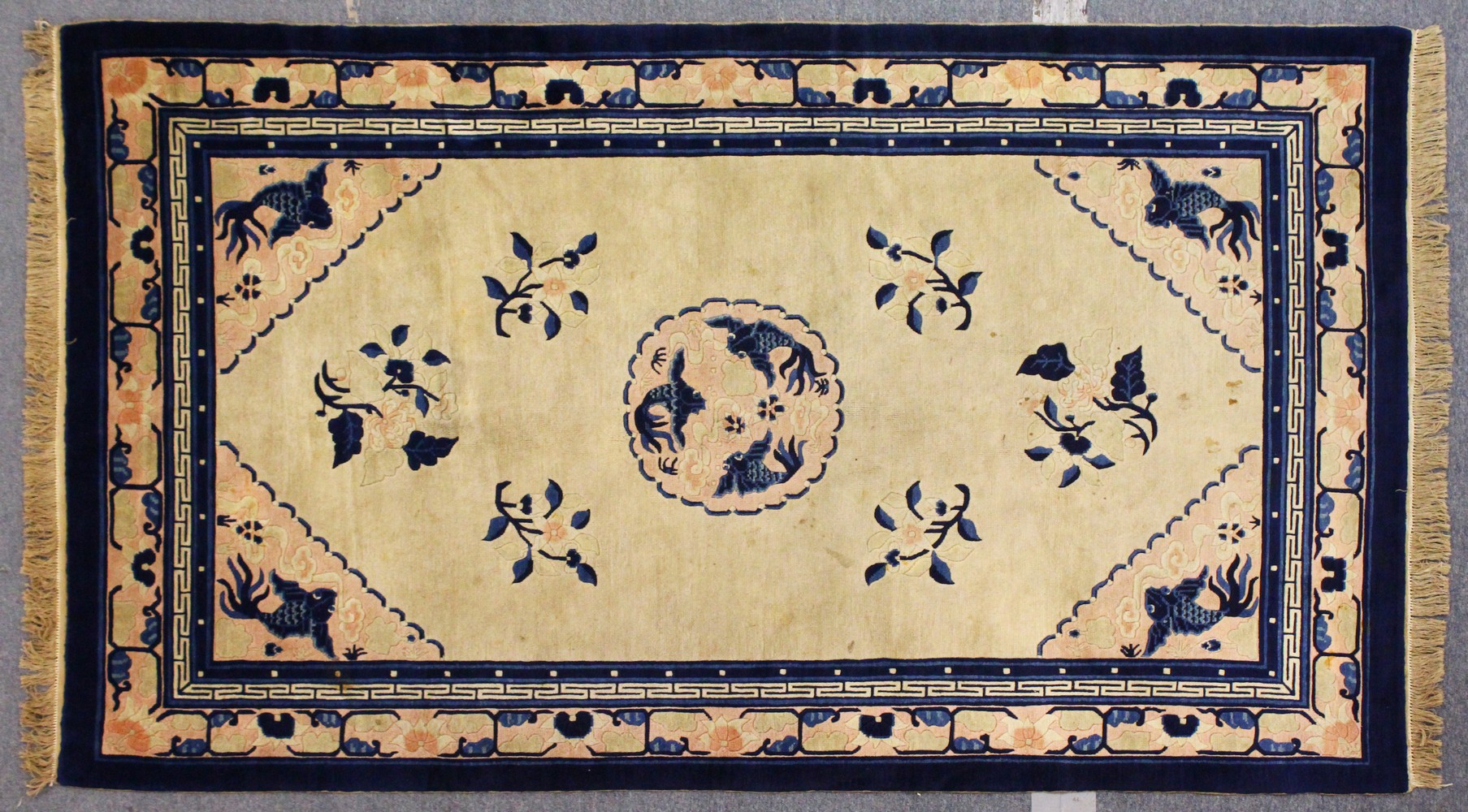 A CHINESE RUG, beige ground, with a central medallion depicting three carp. 7ft 6ins x 4ft 6ins.