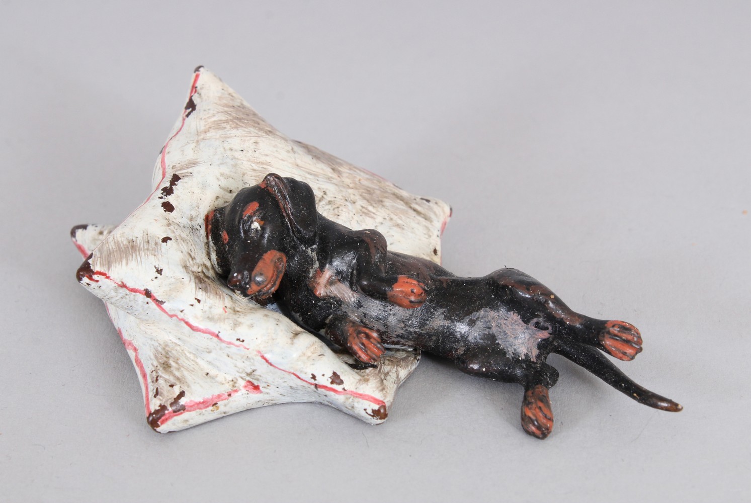 A SMALL COLD PAINTED DOG ON A PILLOW. 3.3ins long.