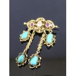 GOLD BROOCH SET WITH A DIAMOND FLANKED BY 2 RUBIES AND HAVING 4 SUSPENDED CABOCHON TURQUOISE