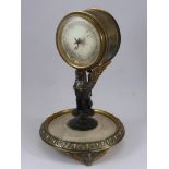 GILT METAL AND ONYX DESK TOP ANEROID BAROMETER, THE CIRCULAR CASE SUPPORTED BY A SPHINX ON A ROUND