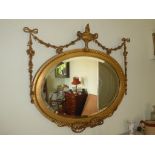LATE 19TH CENTURY OVAL MIRROR WITH GILTWOOD FRAMED DECORATED WITH SWAGS AND A GRECIAN URN, 91 X 83