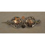 An ornate silver and gilt sweetheart brooch decorated with flowers and leaves,