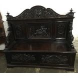 Large late 19th century oak settle with carved panel depicting a man fighting a lion