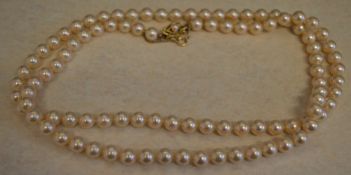 Simulated pearl necklace with an ornate gilt silver clasp and safety chain