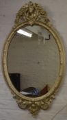 An ornate oval painted wall mirror