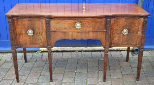 George III serpentine front mahogany sideboard on tapering fluted legs with Adam style carved