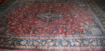 Large Persian red ground Mashad carpet with traditional central medallion design