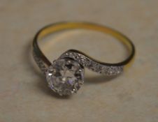 Tested as 18ct gold diamond solitaire ring with ornate twisted shoulders and decorated with diamond