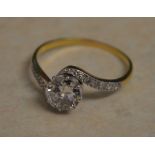 Tested as 18ct gold diamond solitaire ring with ornate twisted shoulders and decorated with diamond