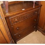 A carved oak chest of three long drawers, an oak side serving trolley, fitted cupboard, on