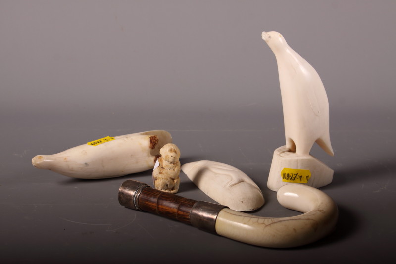 A collection of various sperm whale scrimshaw carvings a carved ivory cane handle with silver collar