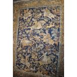 An Indian rug decorated with hunters and tigers on a blue ground with a border of trees and animals,