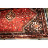 A Qashqai type rug with birds, flowers, trees and central lozenge in shades of red, orange and