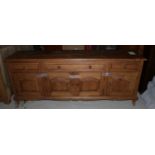 A waxed pine low sideboard, fitted three drawers and cupboards, on shaped supports, 74" wide