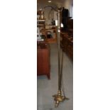 An early 20th century brass standard lamp, on triform platform base and scroll feet, 66"