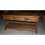 A waxed pine side table, fitted three drawers and undertier, on carved supports, 60" wide