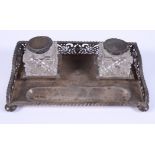 A George V silver inkstand with pierced gallery and crest, fitted two cut glass and silver topped