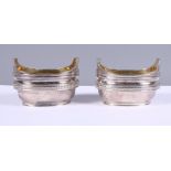 A pair of Georgian silver boat-shaped salts with reeded borders and gilt interiors