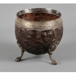 A late 17th century carved coconut cup with silver mounts, on splayed ball and claw feet, makers