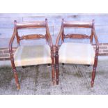 A pair of early 19th century mahogany arch back carver dining chairs with scroll arms and stuffed