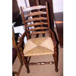 A pair of oak ladder back elbow chairs with rush envelope seats, on turned and stretchered supports