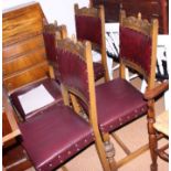 A set of six oak standard dining chairs of 17th century design, upholstered in a dark red leather,