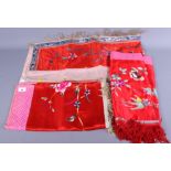 Three Chinese silk embroidered panels with floral designs on a red ground