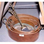 A set of three copper oval two-handled pans, a copper warming pan with turned wood handle, a set