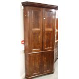 A George III figured mahogany and banded corner cupboard enclosed four panel doors, on bracket feet,